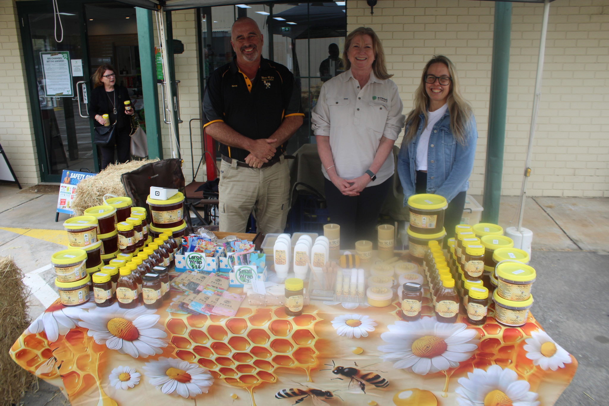 Scott Williams from Braidwood business Bees R’ Us (left), Bowral Co-Op’s Xanthe Herps and Market Organiser Lauren O’Brien at the Bees R’ Us stall. (Photo: Antony Dubber)