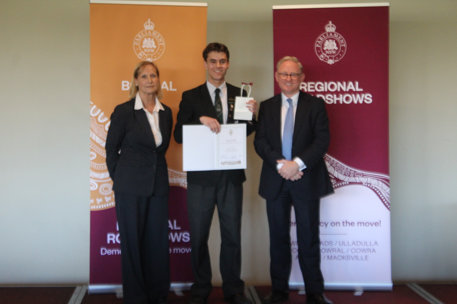 William Norman presented with his winner’s certificate and voucher by Member for Wollondilly, Judy Hannan (left) and President of the NSW Legislative Council, The Honourable Ben Franklin. (Photo: Antony Dubber)